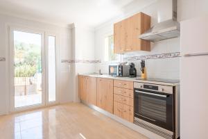 a kitchen with white walls and wooden cabinets and a window at Ferrera Soul 1b in Santanyi