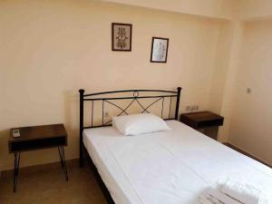 a bedroom with a bed with two nightstands and two tables at Emma's studio house by Kapsali beach in Kapsali