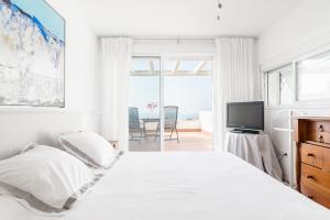 a white bedroom with a bed and a television at Casa Fuente del Sol in Conil de la Frontera +27 photos
