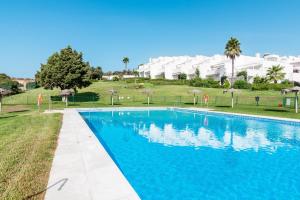 a blue swimming pool in front of a building at Casa Fuente del Sol in Conil de la Frontera