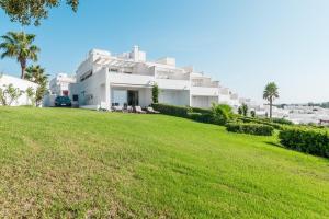 a white house on a hill with a green lawn at Casa Fuente del Sol in Conil de la Frontera