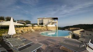a large swimming pool with chairs and a umbrella at Apartment Simone in Baja Sardinia