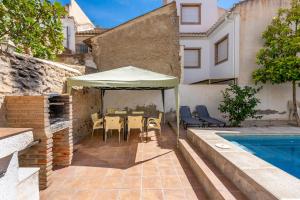 a patio with a table and umbrella next to a swimming pool at Casa Adriana con piscina in Murchas