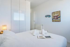 a white bedroom with a bed with a book on it at Tu Paraíso Privado Con Piscina in Albolote +25 photos