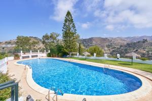 a swimming pool in a yard with mountains in the background at Atalaya in Almuñécar