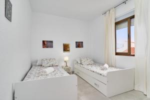 two beds in a white room with a window at Atalaya in Almuñécar +23 photos
