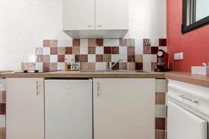 a kitchen with white cabinets and a sink at Les Gîtes W elles come in Cotignac