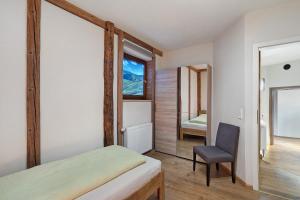 a bedroom with a bed and a chair and a mirror at Schwarzwald-Lodge - hundefreundlich in Kappelrodeck