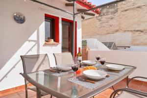a glass table with chairs and wine glasses on a balcony at Estudio Quorum, centro de Nerja in Nerja