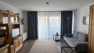 a living room with a couch and a television at Ferienwohnung Voges mit Pool in Bad Lauterberg +18 photos