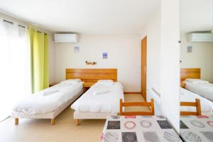 a room with three beds and a window at Les Mimosas - Appartement 12 in Cazaubon
