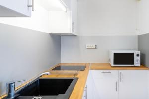 a kitchen with a sink and a microwave at Les Mimosas - Appartement 12 in Cazaubon