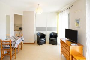 a living room with a table and chairs and a television at Les Mimosas - Appartement 12 in Cazaubon +12 photos