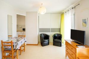 a living room with a table and chairs and a television at Les Mimosas - Appartement 12 in Cazaubon