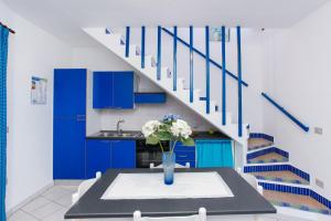 a kitchen with blue cabinets and a table with a vase of flowers at mirtagru appartamento dell'oleandro in Budoni