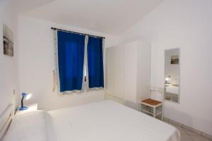 a white bedroom with a bed and a blue window at mirtagru appartamento dell'oleandro in Budoni