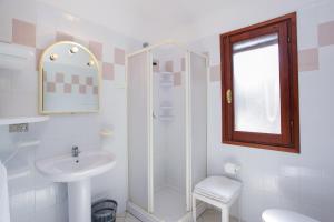 a white bathroom with a sink and a shower at mirtagru appartamento dell'oleandro in Budoni +9 photos