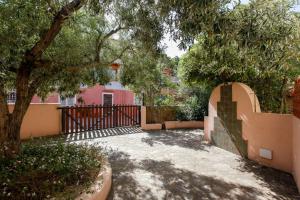 a gate to a pink house with a tree at mirtagru appartamento dell'oleandro in Budoni