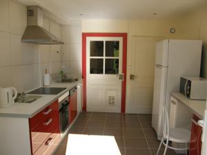 a kitchen with a white refrigerator and a red door at Gîte Ancien Relais De Poste in Les Rousses