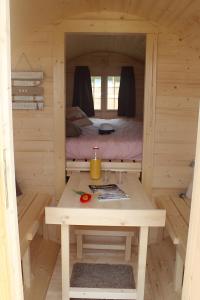 a wooden cabin with a table and a bed in it at Barrel Papilles En Escapade in Sevremont +10 photos