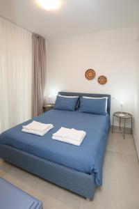 a bedroom with a blue bed with towels on it at Appartamento Ralf - In Centro in Castelsardo