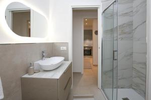 a bathroom with a sink and a glass shower at Appartamento Ralf - In Centro in Castelsardo