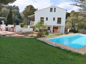 a white house with a swimming pool in front of a yard at Araucaria in Denia