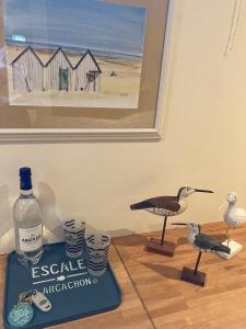 two seagulls on a table with a book and a bottle at Chambre d'hotes La Rambleur in La Teste-de-Buch
