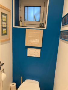 a bathroom with a toilet and a blue wall at Chambre d'hotes La Rambleur in La Teste-de-Buch