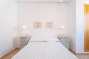 a white bedroom with two night stands and a bed at Mont Pele in Cullera