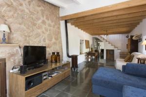 a living room with a tv and a blue couch at Sóller Es Cocó in La Figuera