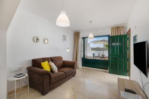 a living room with a brown couch and a green door at Sin Prisa, con Brisa in Costa Teguise