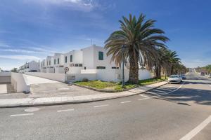 a street with a white building and palm trees at Sin Prisa, con Brisa in Costa Teguise