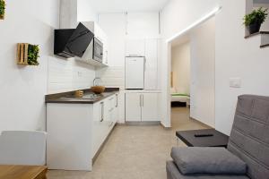 a small kitchen with white cabinets and a couch at Jardin Cardona in Arucas