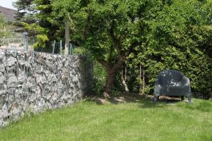 a chair sitting in the grass next to a stone wall at Grimm's Lodge in Lörrach