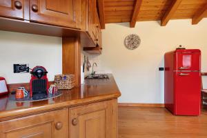 a kitchen with a red refrigerator and wooden cabinets at La Mansardina - Aosta in Aosta