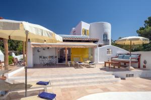a house with a patio with chairs and umbrellas at Villa Torre Xanchu in Sant Josep de sa Talaia