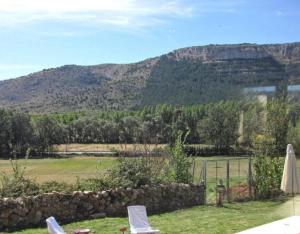 a garden with two chairs and a fence and mountains at Vivir en el Campo in Cidones