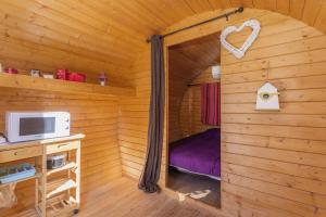 ein kleines Zimmer mit einem Bett in einer Blockhütte in der Unterkunft Barrel Violet in Saint-André
