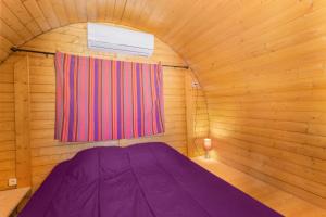 ein lila Bett in einem Holzzimmer mit Fenster in der Unterkunft Barrel Violet in Saint-André + 3 Fotos