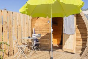 ein grüner Sonnenschirm auf einer Terrasse mit Tisch und Stühlen in der Unterkunft Barrel Violet in Saint-André