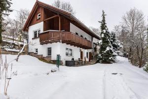 a house in the snow with a snow covered driveway at Ferienwohnung Am Schleifenbach in Saalfeld