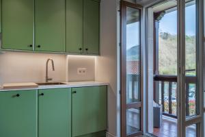 a kitchen with green cabinets and a sliding glass door at 'Salmosalar' Cangas de Onís in Cangas de Onís +20 photos