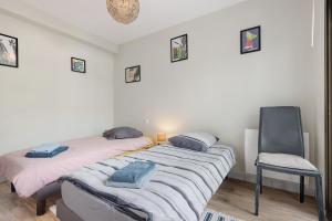 a bedroom with two beds and a chair in it at Joli appartement quartier artistes in Camaret-sur-Mer