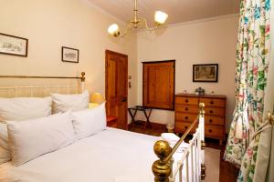 a bedroom with a white bed and a dresser at De Kothuize 166 in Graaff-Reinet