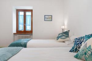 two beds in a room with white walls and a window at Vallelaghi Escape in Terlago