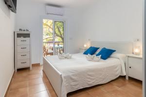 a white bedroom with a large white bed with blue pillows at La caseta de Sa Riera in Begur