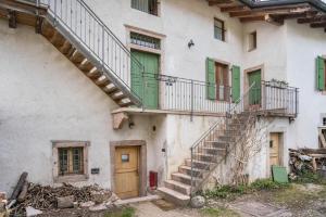 an old building with a staircase and green doors at Vallelaghi Escape in Terlago