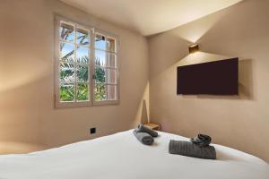a bedroom with a bed with a flat screen tv at Le Cocon Blanc - T3 - Gassin in Gassin