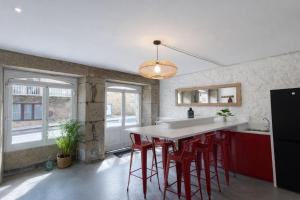 a kitchen with red stools and a white counter top at Therma Pilgrim Hostel in Caldas de Reis